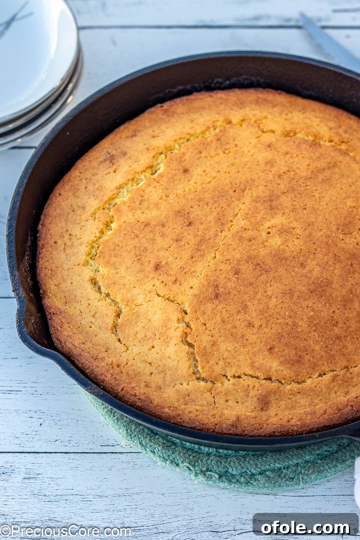 Hearty cornbread baked to golden perfection in a traditional cast iron skillet, ready to be sliced.