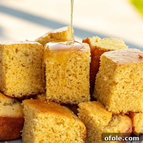Square slices of cornbread without buttermilk with honey drizzling on top.