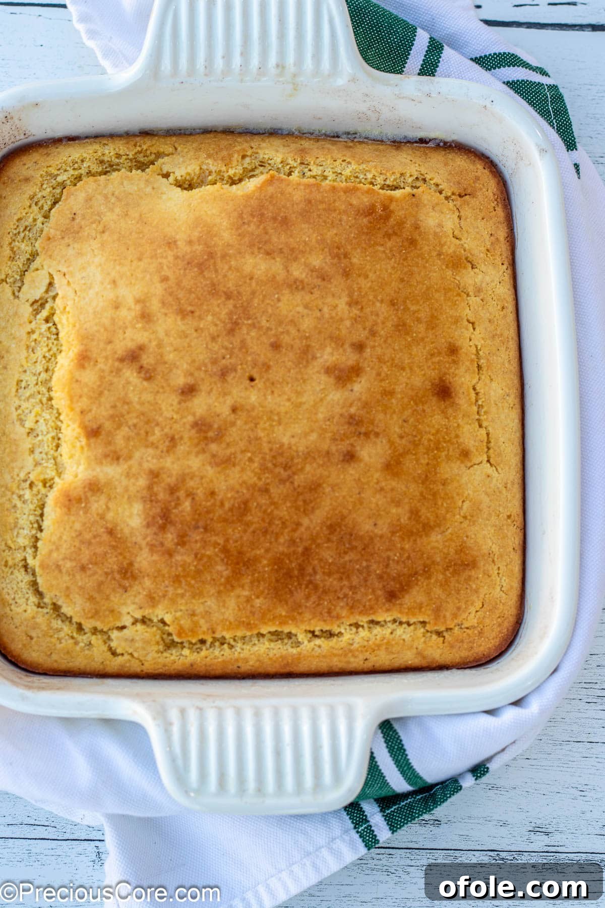 Freshly baked cornbread cooling in a square glass baking dish, sliced and ready to serve.