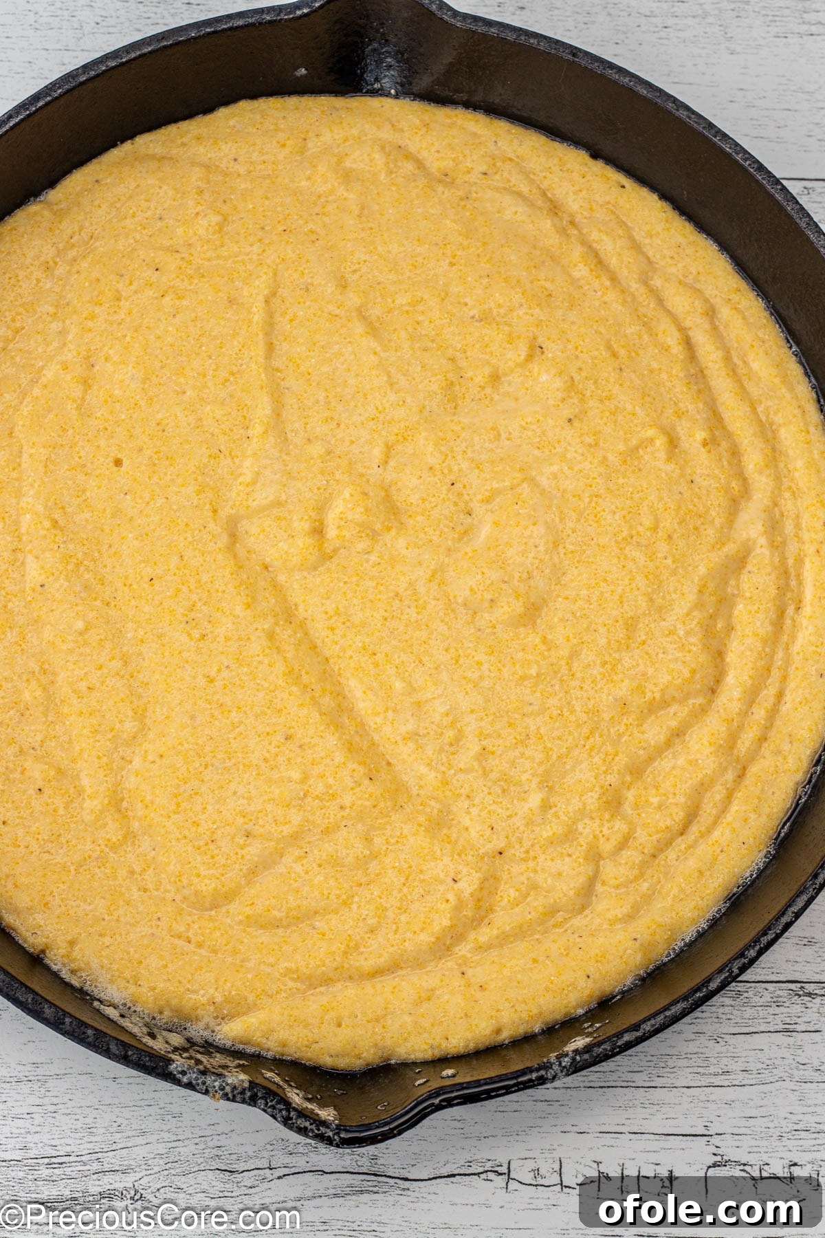 Smooth cornbread batter evenly spread in a cast iron skillet, ready for baking.