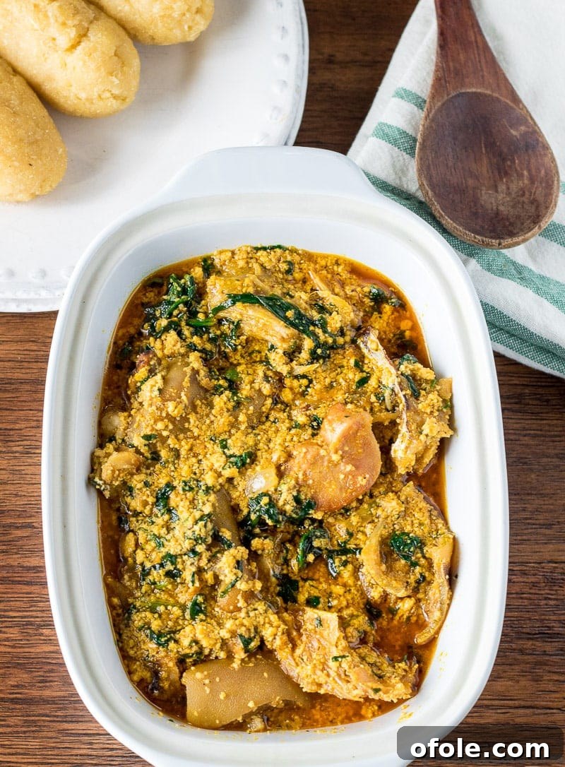 Egusi: Africa's Signature Stew 2 Egusi soup with meat in a white bowl, garnished with greens.