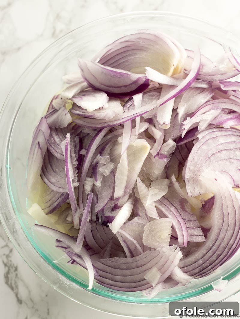 Four large onions thinly sliced, ready for caramelization in a Senegalese Poulet Yassa recipe