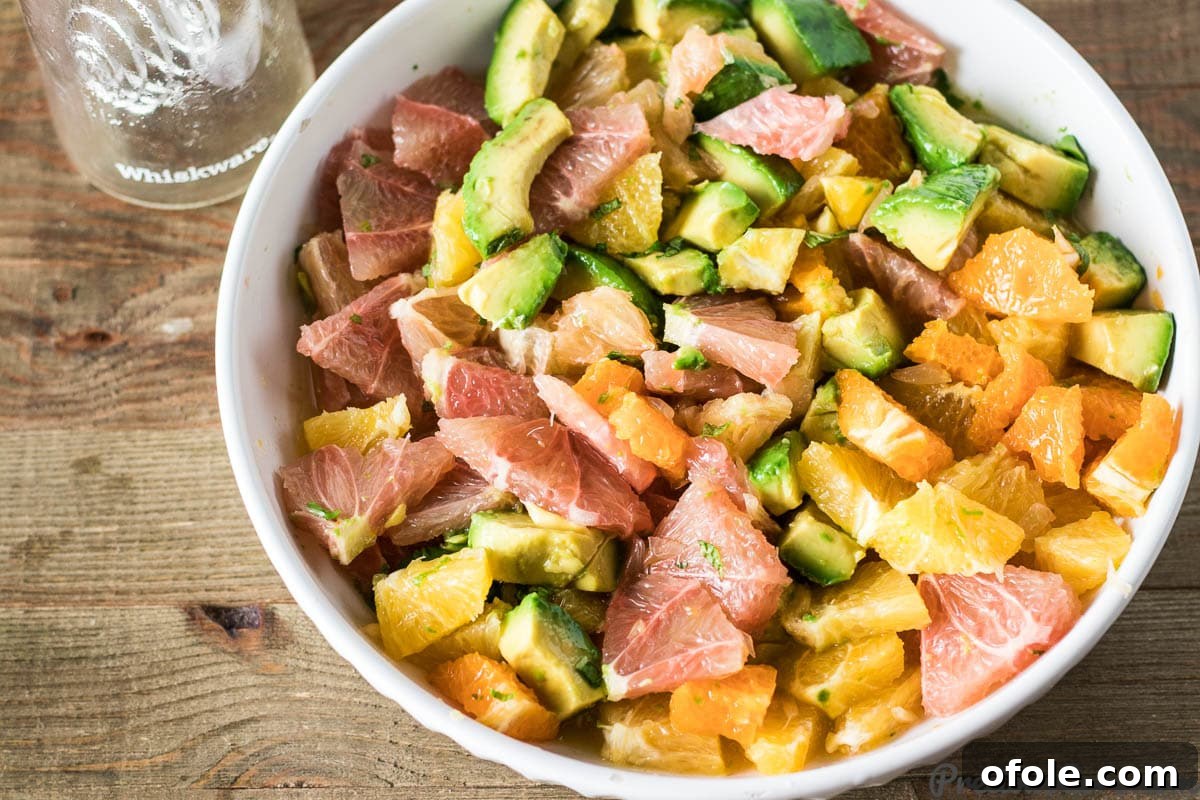 A wide shot of a colourful tossed Citrus Salad with Avocado in a bowl, perfect for a gathering.