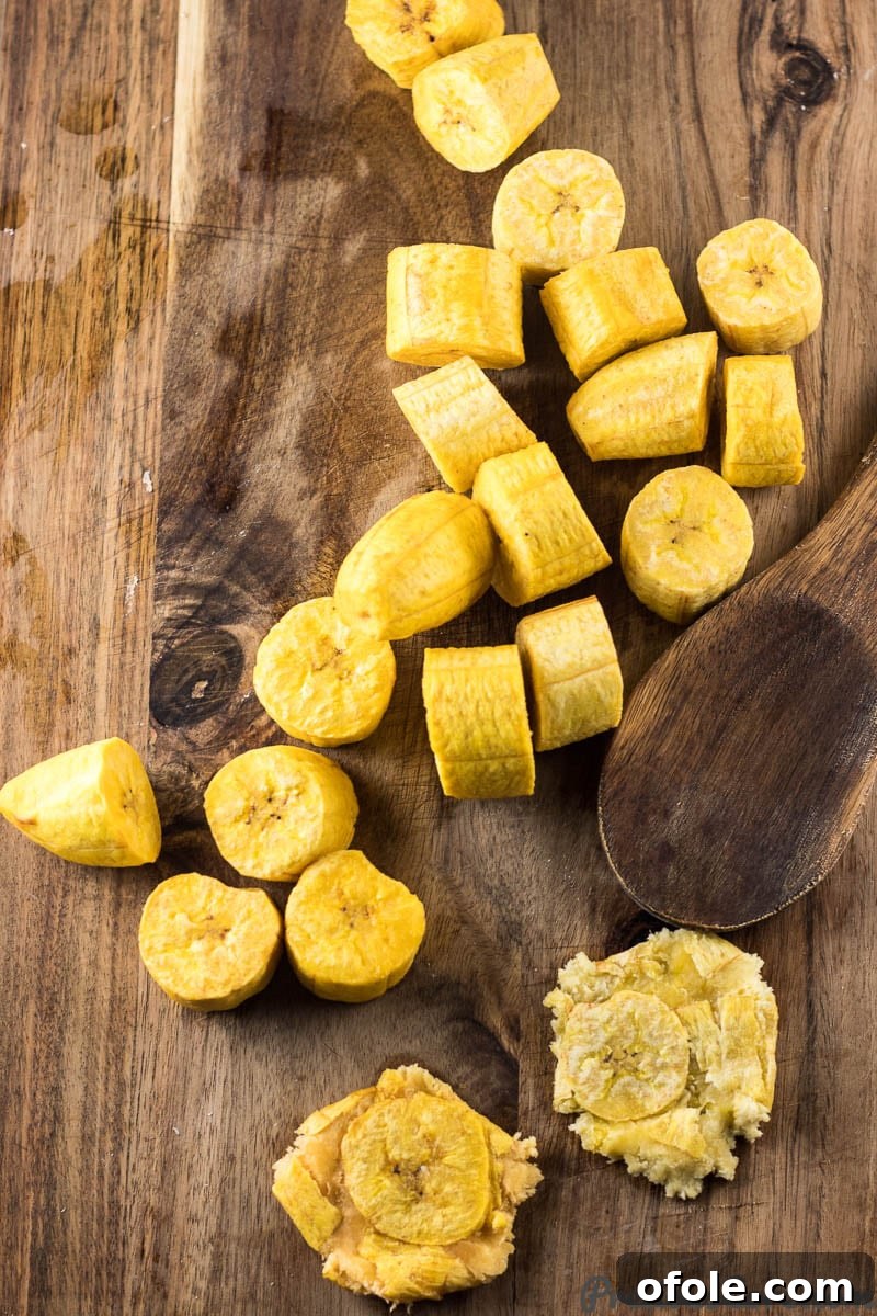 Golden Crispy Tostones The Ultimate Twice-Fried Plantain Recipe 6 Wooden spoon with flattened plantains.