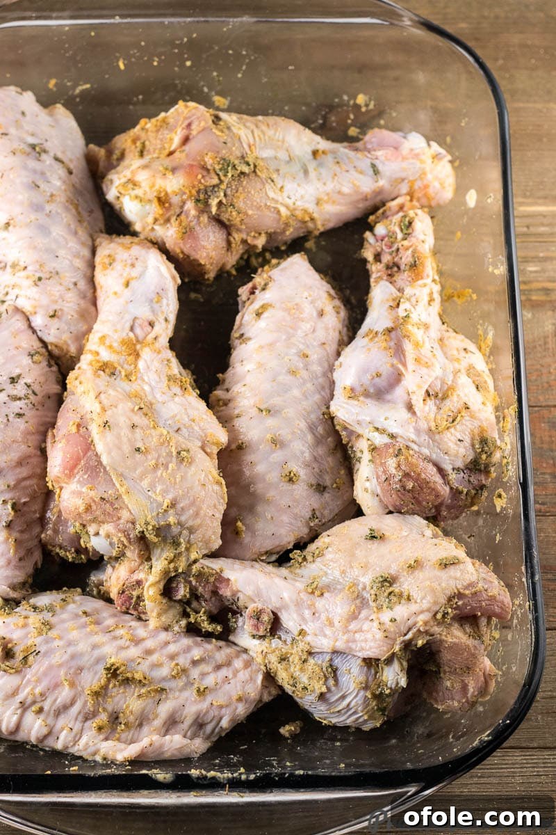 Golden Baked Turkey Wings 6 Raw turkey wings generously seasoned with herbs and spices, arranged in a baking dish, ready for the oven.