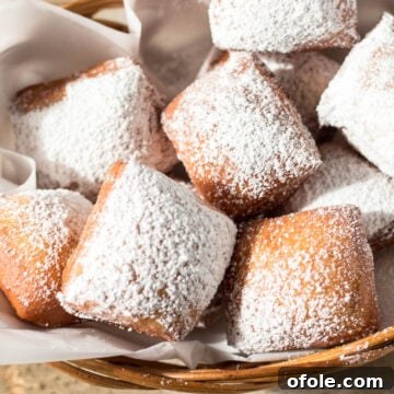 Basket of freshly made beignets, dusted with powdered sugar.