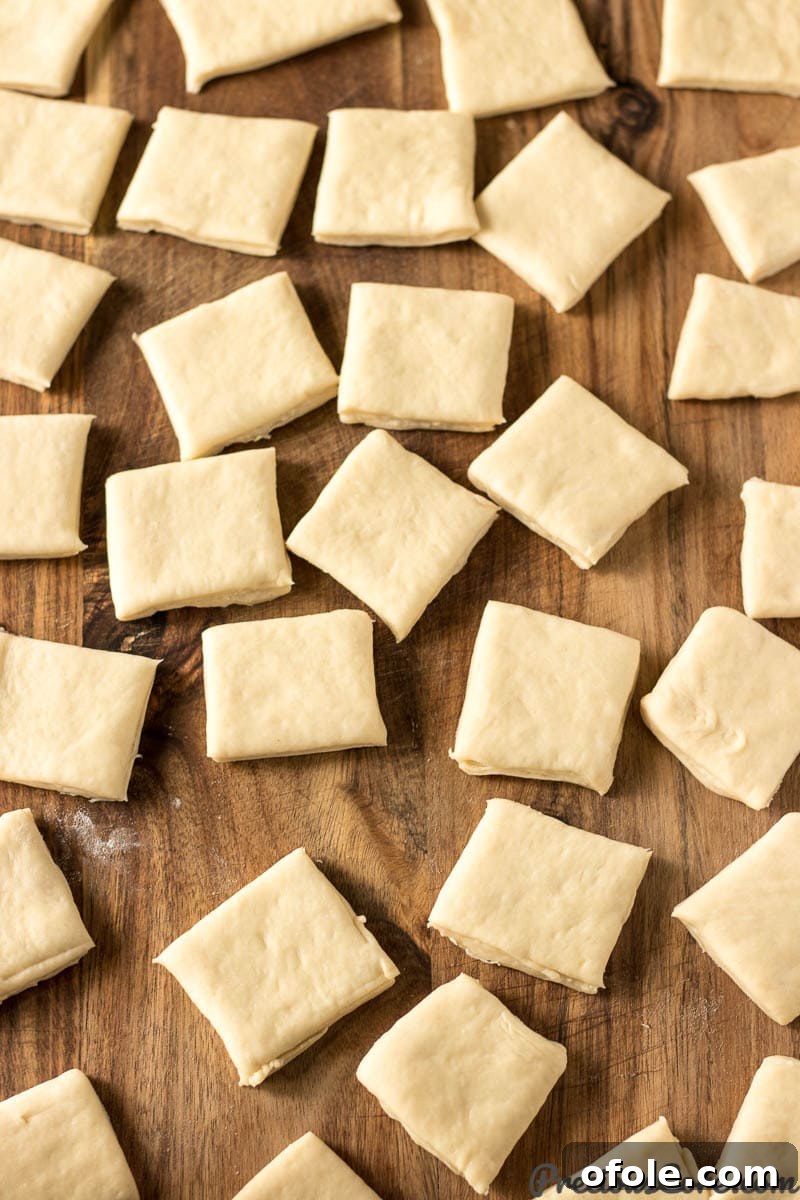 Close-up of perfectly cut beignet dough squares arranged on a wooden board.