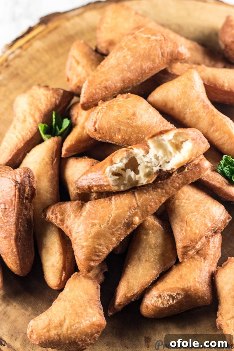 Mandazi East African Fried Pastry 3 Pile of Mandazi, one of which is missing a bite.