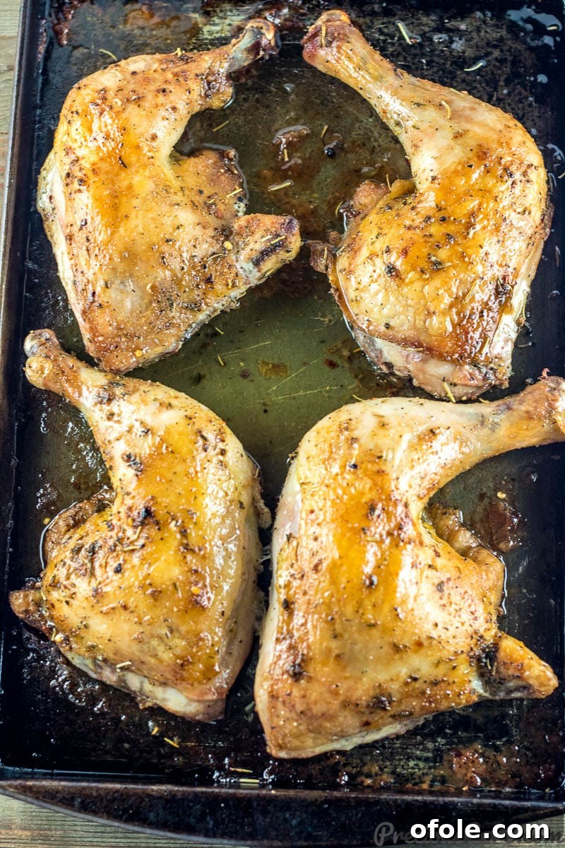 Crispy Skin Chicken Leg Quarters 3 Perfectly baked chicken leg quarters on a baking tray, with flavorful juices collected at the bottom.