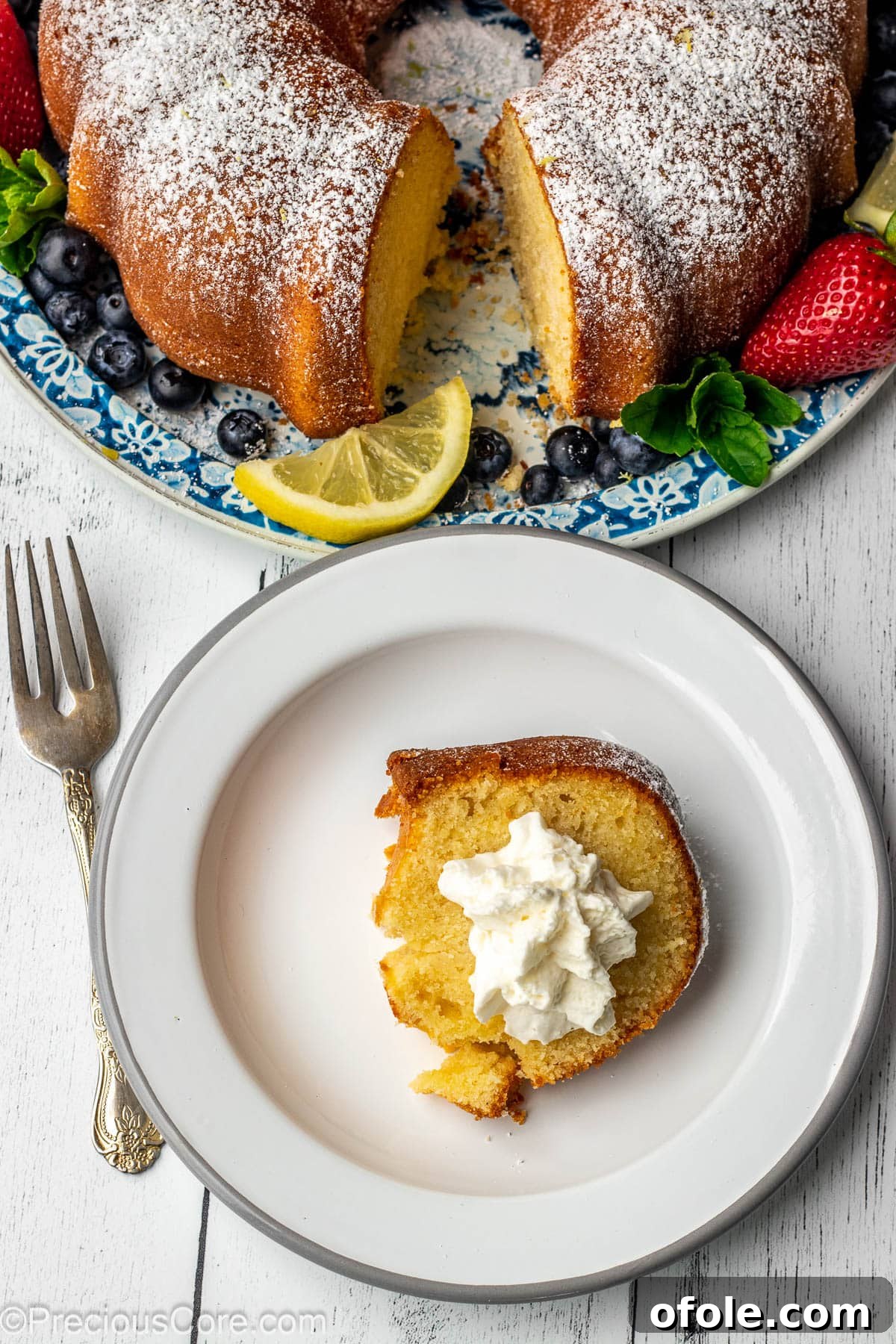 Zesty Southern Lemon Pound Cake 11 A close-up of a delightful slice of lemon pound cake generously topped with whipped cream, ready to be enjoyed.