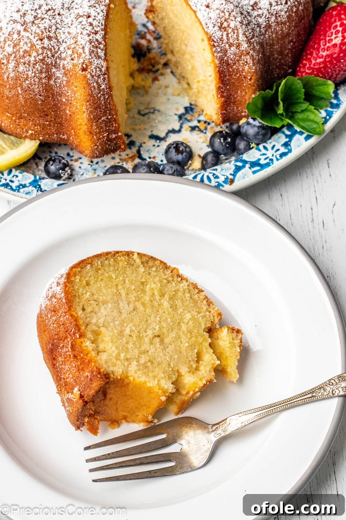 Zesty Southern Lemon Pound Cake 4 A close-up of a perfectly baked slice of lemon pound cake on a pristine white plate, showcasing its moist texture.
