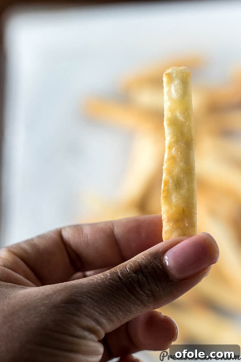 Irresistibly Crispy Yuca Fries 3 Hand holding a perfectly golden and crispy yuca fry.