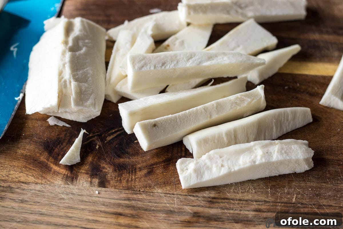 Irresistibly Crispy Yuca Fries 5 Peeled yuca neatly cut into fry-sized pieces on a chopping board.