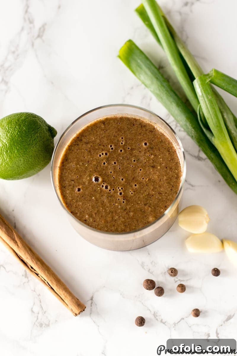 Jamaican Jerk: The Island's Fiery Secret 4 Glass of Jamaican jerk seasoning surrounded by fresh ingredients like garlic and lime.