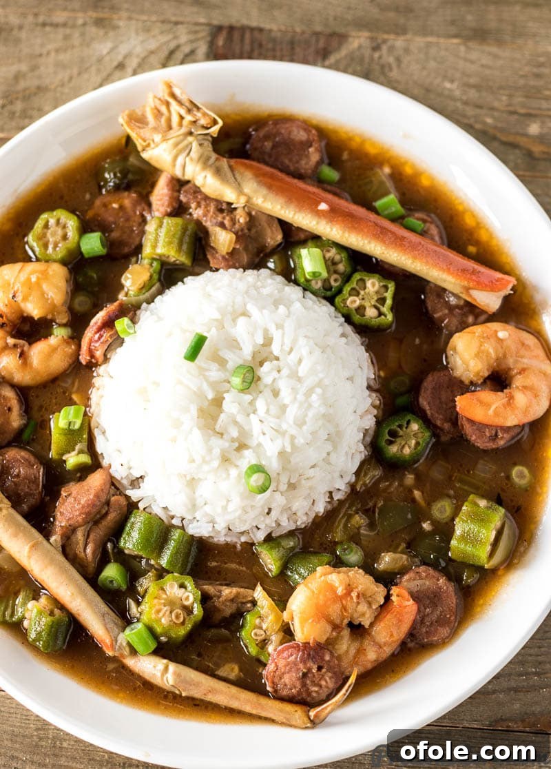 A steaming bowl of authentic Seafood Gumbo with succulent shrimp, crab legs, and fluffy white rice, ready to be enjoyed.