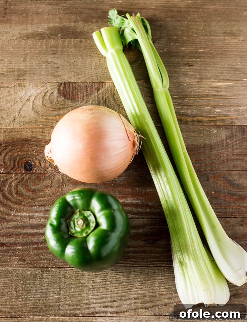 Finely diced onions, green bell pepper, and celery, the 'holy trinity' of Cajun and Creole cuisine, laid out on a cutting board.