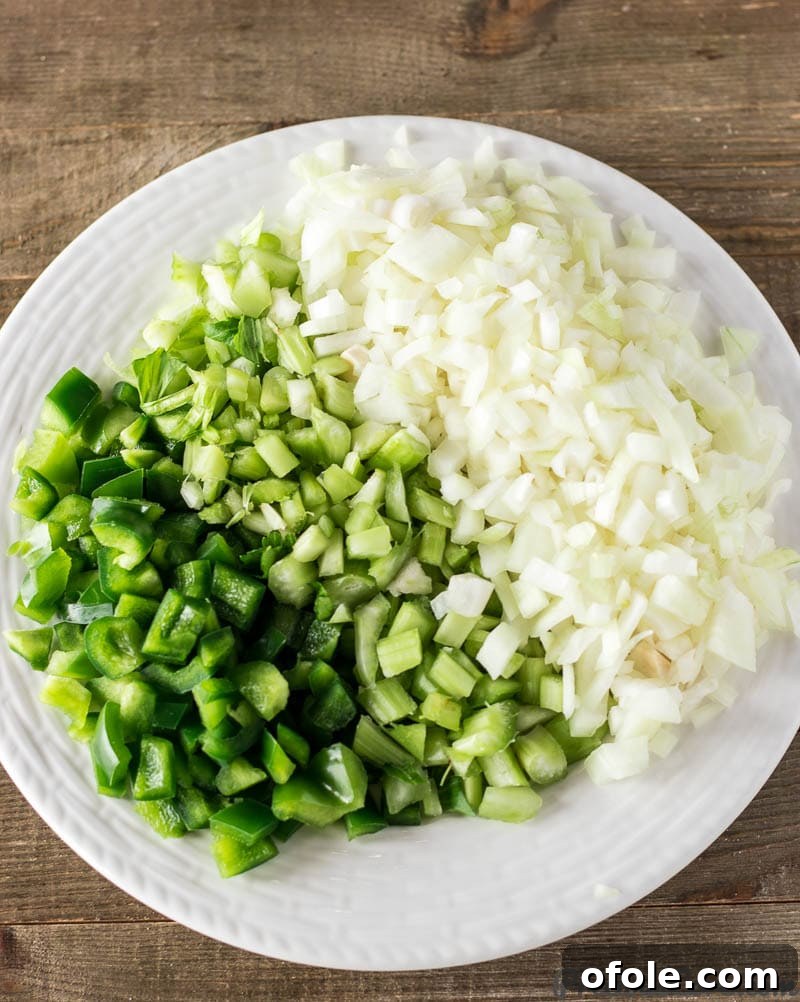 Diced fresh onions, crisp celery stalks, and a vibrant bell pepper, the 'holy trinity' ingredients, ready for gumbo preparation.