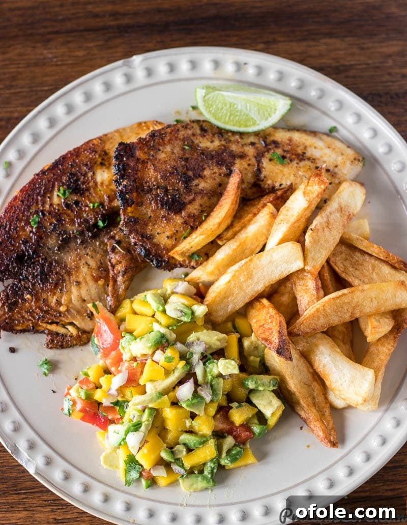Grilled fish and a lime wedge with a generous serving of mango avocado salsa.