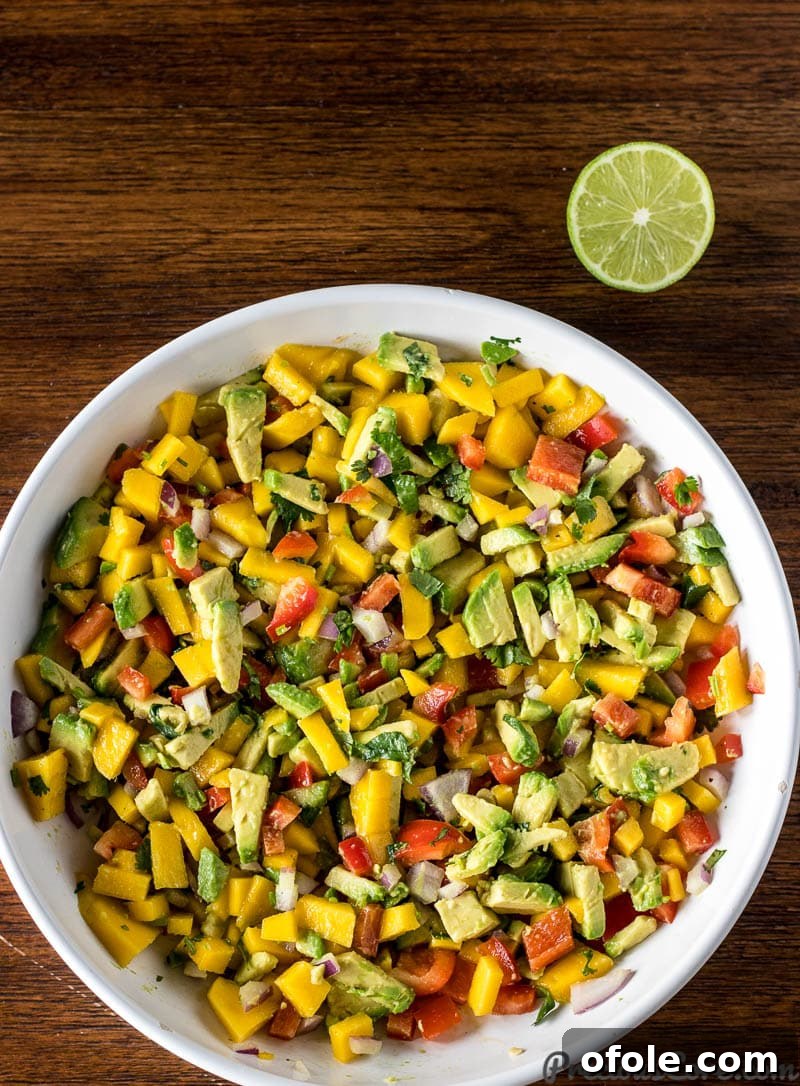 Mango Avocado Salsa in a large white bowl, garnished with a lime half.