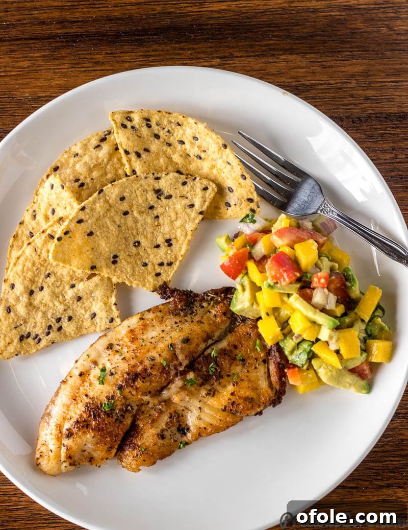 Mango Avocado Salsa served on a plate with grilled fish and tortilla chips, garnished with cilantro.