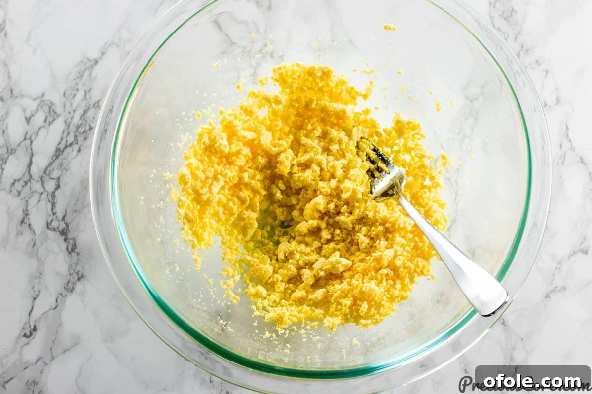 Southern Charm Deviled Eggs 7 Mashing egg yolks for deviled eggs filling.