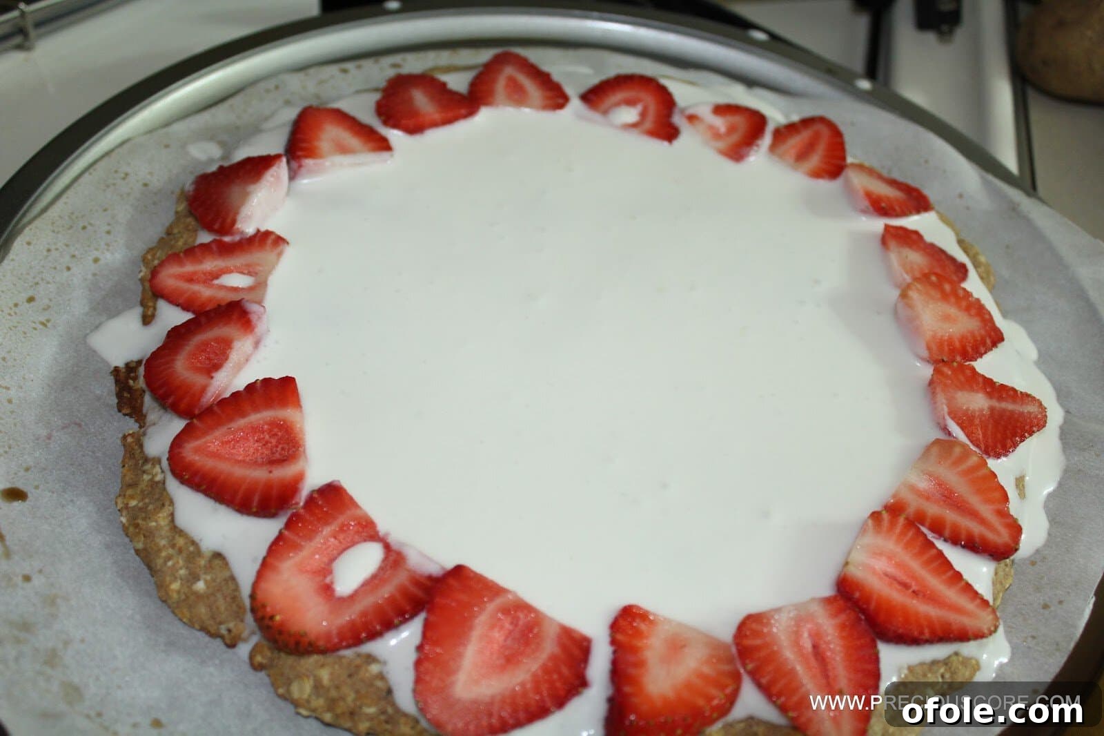 Topping healthy fruit pizza with fresh sliced fruits