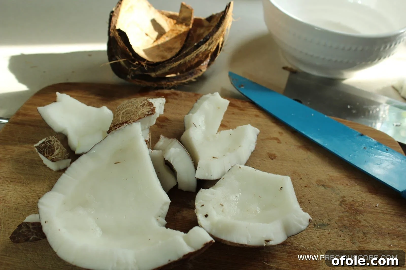 Removing coconut flesh from its shell for shredding