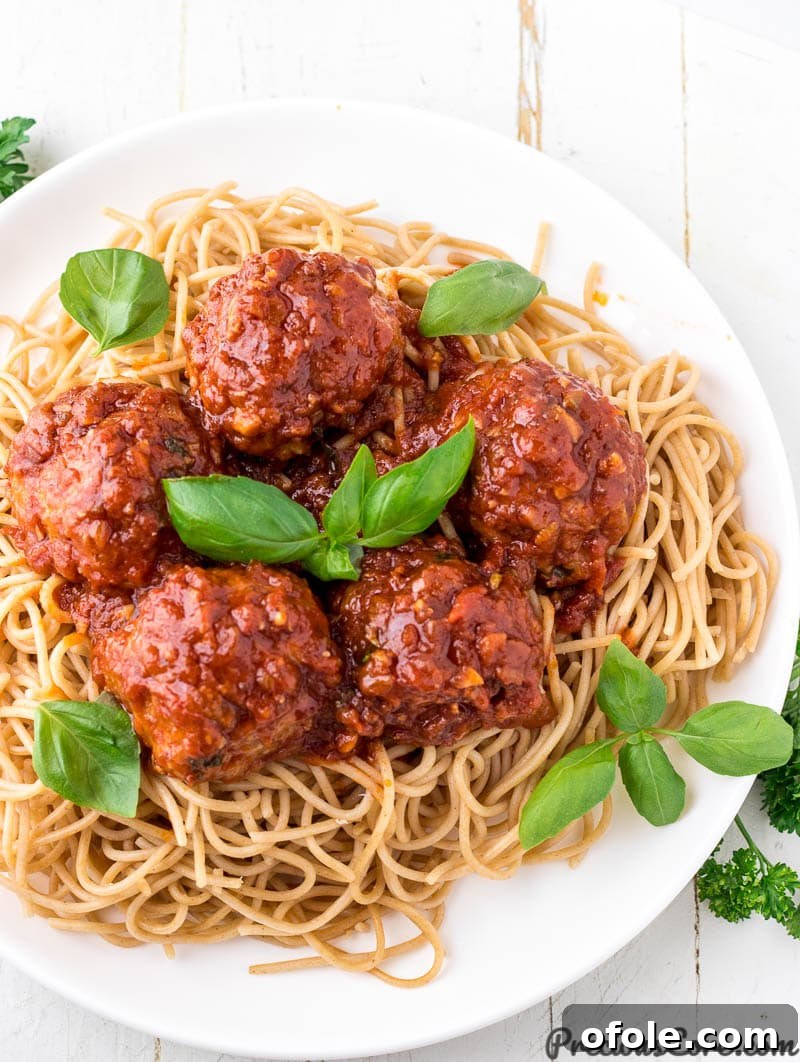 Savory Chicken Bites 2 Perfectly cooked chicken meatballs served over a bed of al dente spaghetti, generously coated in a rich tomato sauce, garnished with fresh herbs.