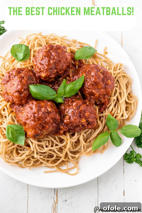 A top-down view of tender chicken meatballs generously coated in rich tomato sauce, served intertwined with perfectly cooked spaghetti.