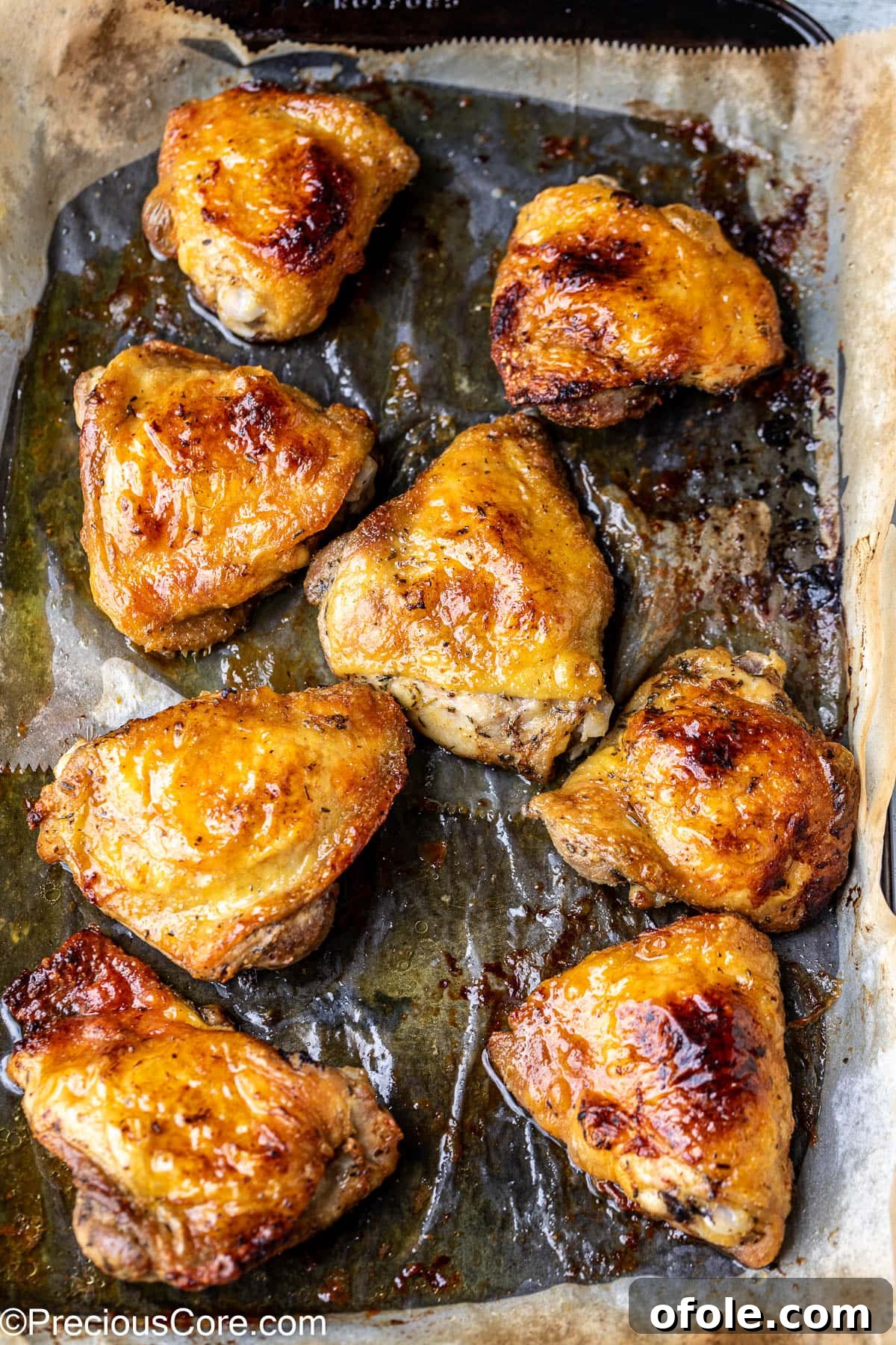 Broiled mayonnaise chicken thighs on a baking sheet lined with parchment paper, golden and glistening.