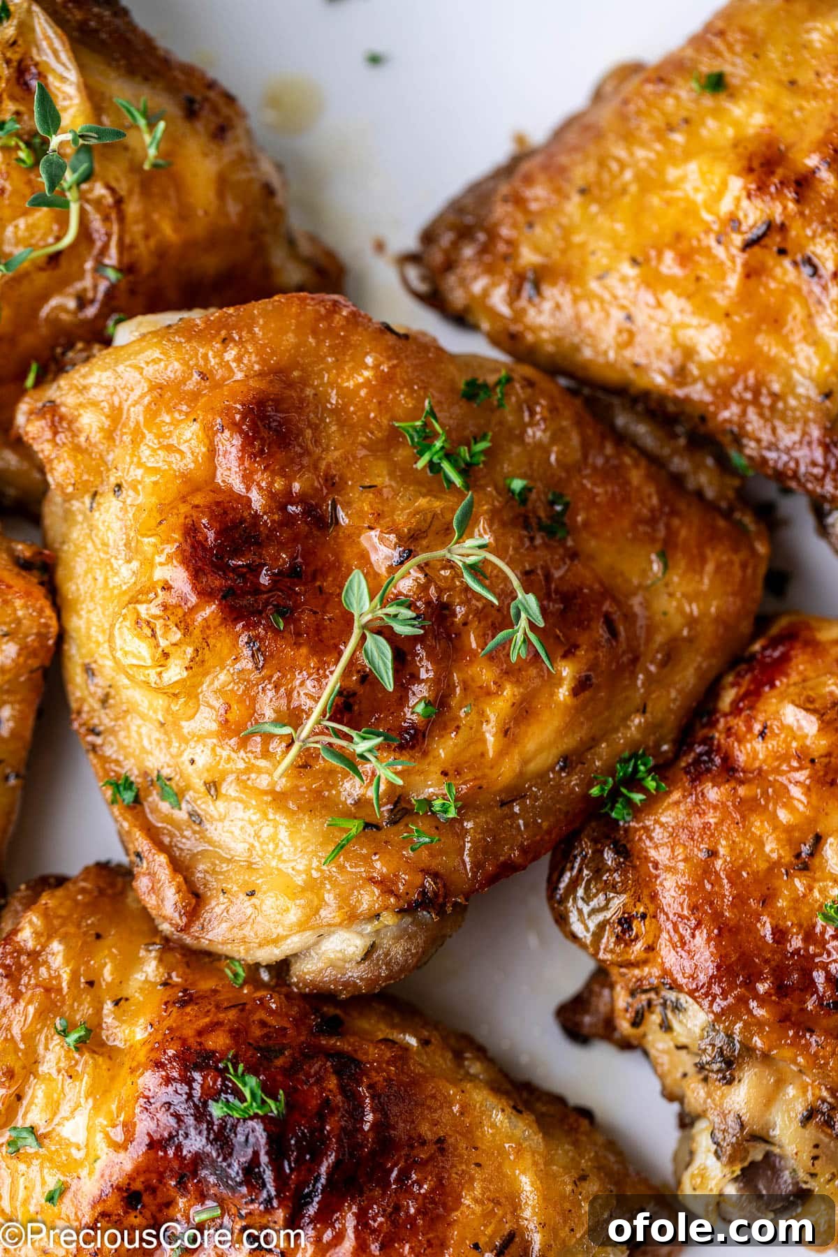 Close up on a golden brown chicken thigh, surrounded by other chicken thighs, beautifully cooked.