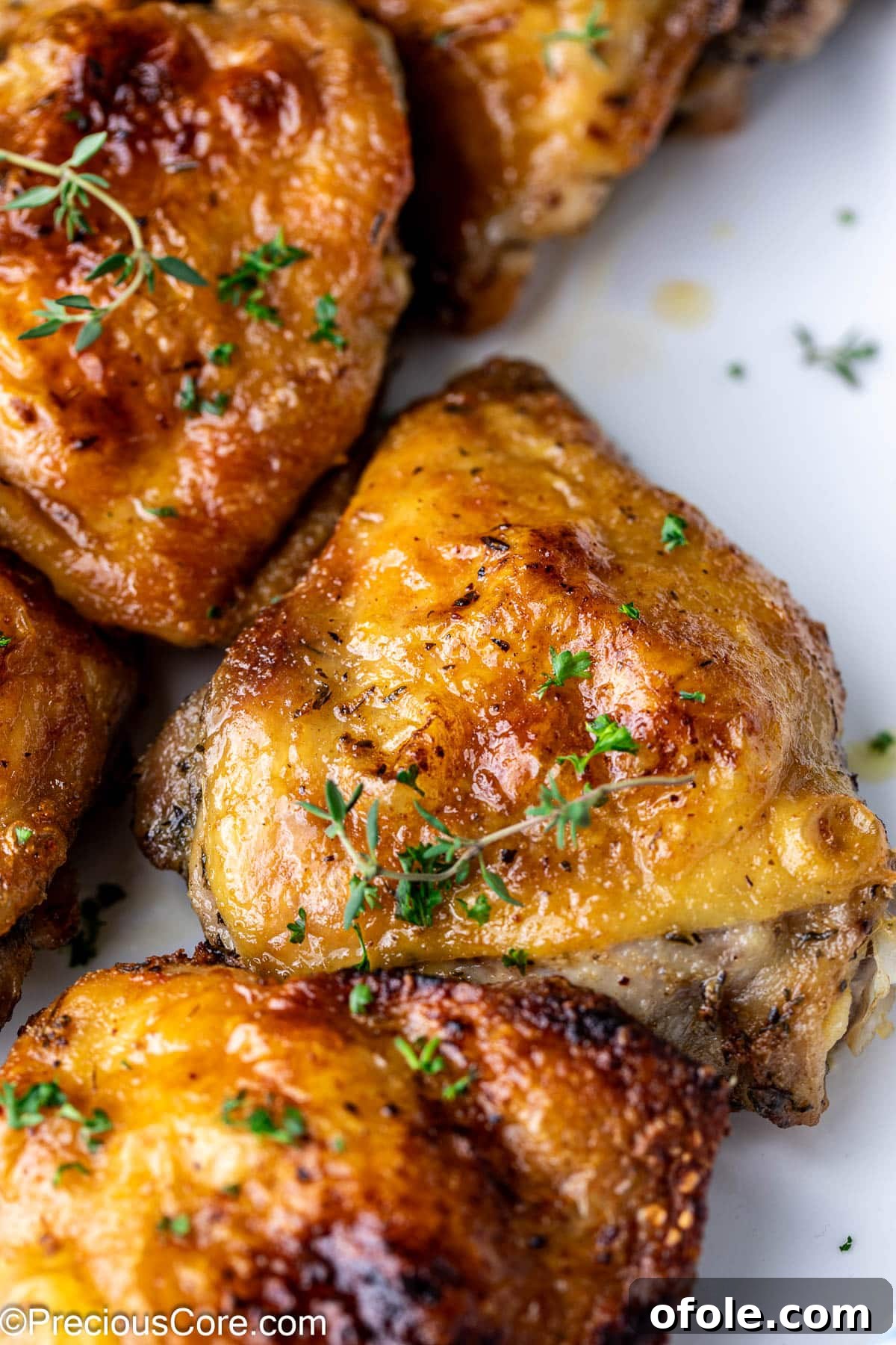 Zoom in on a chicken thigh garnished with fresh thyme, emphasizing its golden-brown color.