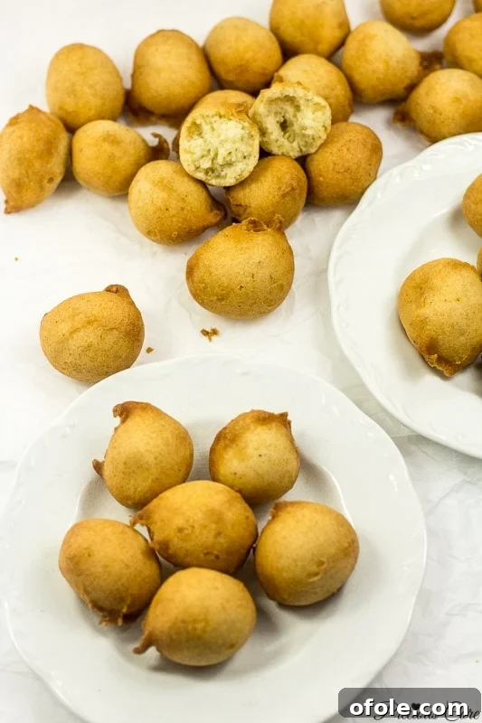 Two white plates of golden brown Cameroonian doughnuts on parchment paper.