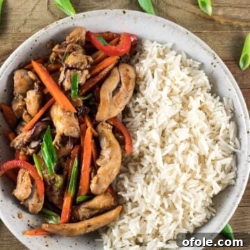 Quick Chicken Stir Fry 2 A vibrant bowl of Easy Chicken Stir Fry served with fluffy Mahatma Ready to Serve Rice, garnished with fresh herbs.