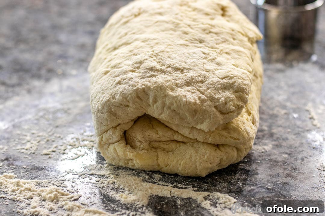Biscuit dough folded into thirds on a floured surface, demonstrating the layering technique.