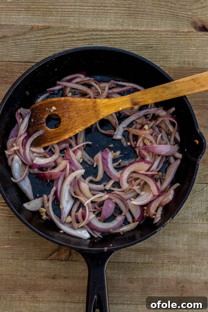 Onions and minced garlic sizzling in melted butter in a skillet, beginning to soften and turn fragrant.