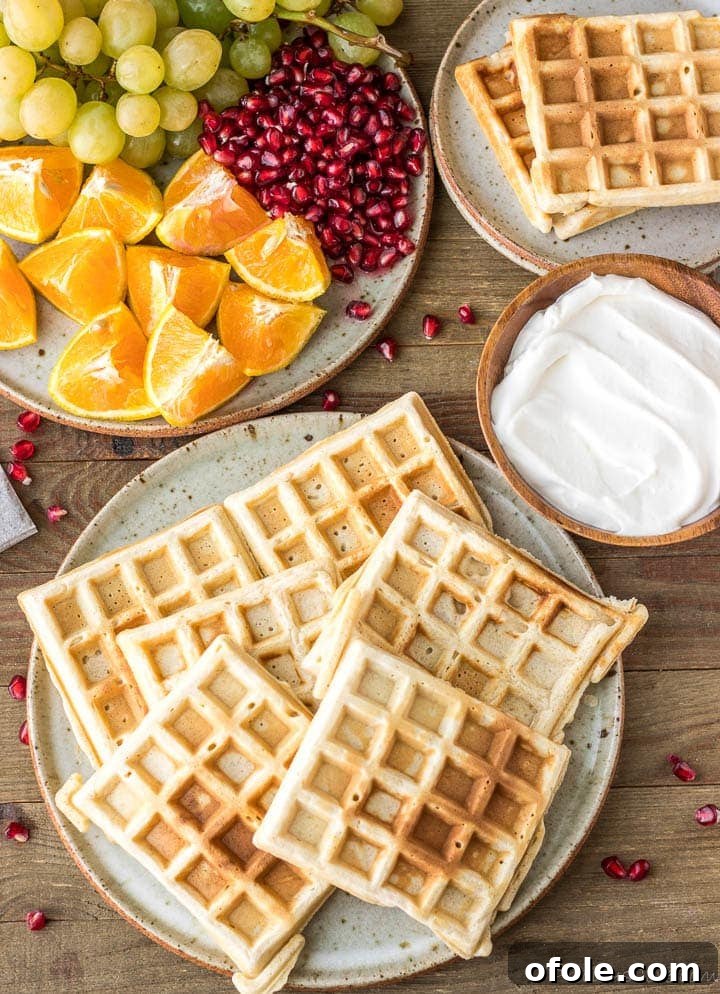 Kitchen-Crafted Waffles 4 Stack of golden homemade waffles on a plate with a side of whipped cream.