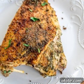 A large roasted turkey thigh on a plate, perfectly cooked and tender.