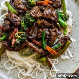 Beef stir fry over noodles, colorful and saucy.