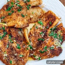Lemon butter tilapia fillets on a plate, glistening and ready to serve.
