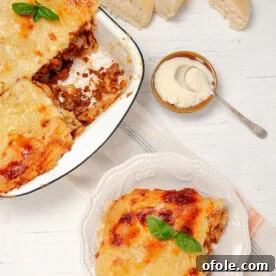 Slice of Lasagna on a plate with a bowl of freshly baked lasagna on the side, showing the layers.