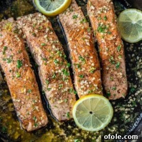 4 pieces of salmon in a cast iron skillet, beautifully cooked with lemon butter.