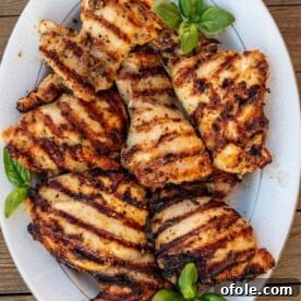 Grilled boneless chicken thighs on a platter, perfectly charred and juicy.