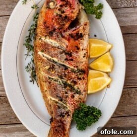 Grilled whole red snapper on a platter, a beautiful and flavorful seafood presentation.