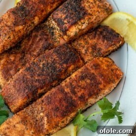 Four grilled salmon fillets on a serving platter, showing perfect grill marks.