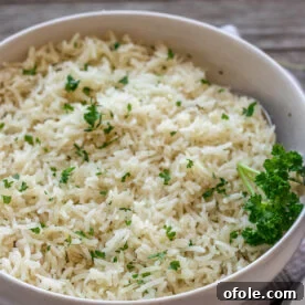 A bowl of garlic herb rice topped with minced fresh parsley, a fragrant side dish.