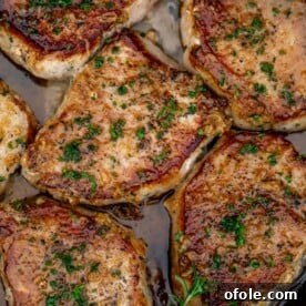 Pan seared boneless pork chops in a cast iron pan with butter underneath, golden and tender.