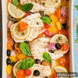White fish fillets in a casserole dish baked with veggies, a healthy Mediterranean-inspired meal.