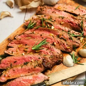 Sliced pan seared flank steak on a cutting board, juicy and tender.
