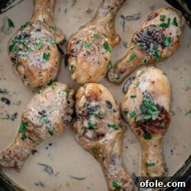 Chicken drumsticks in creamy sauce in a cast iron skillet, a comforting family meal.
